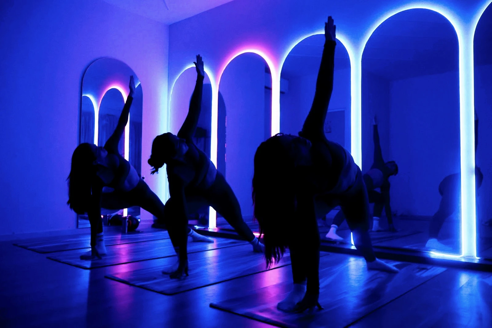 Clase grupal en el estudio iluminado con arcos de neón azul