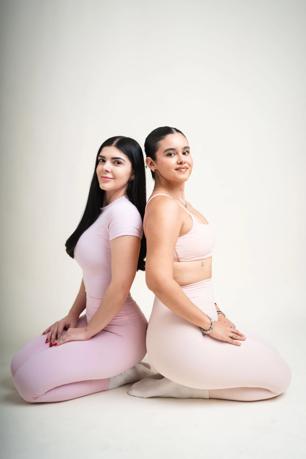 Dos alumnas sentadas espalda con espalda sobre el mat